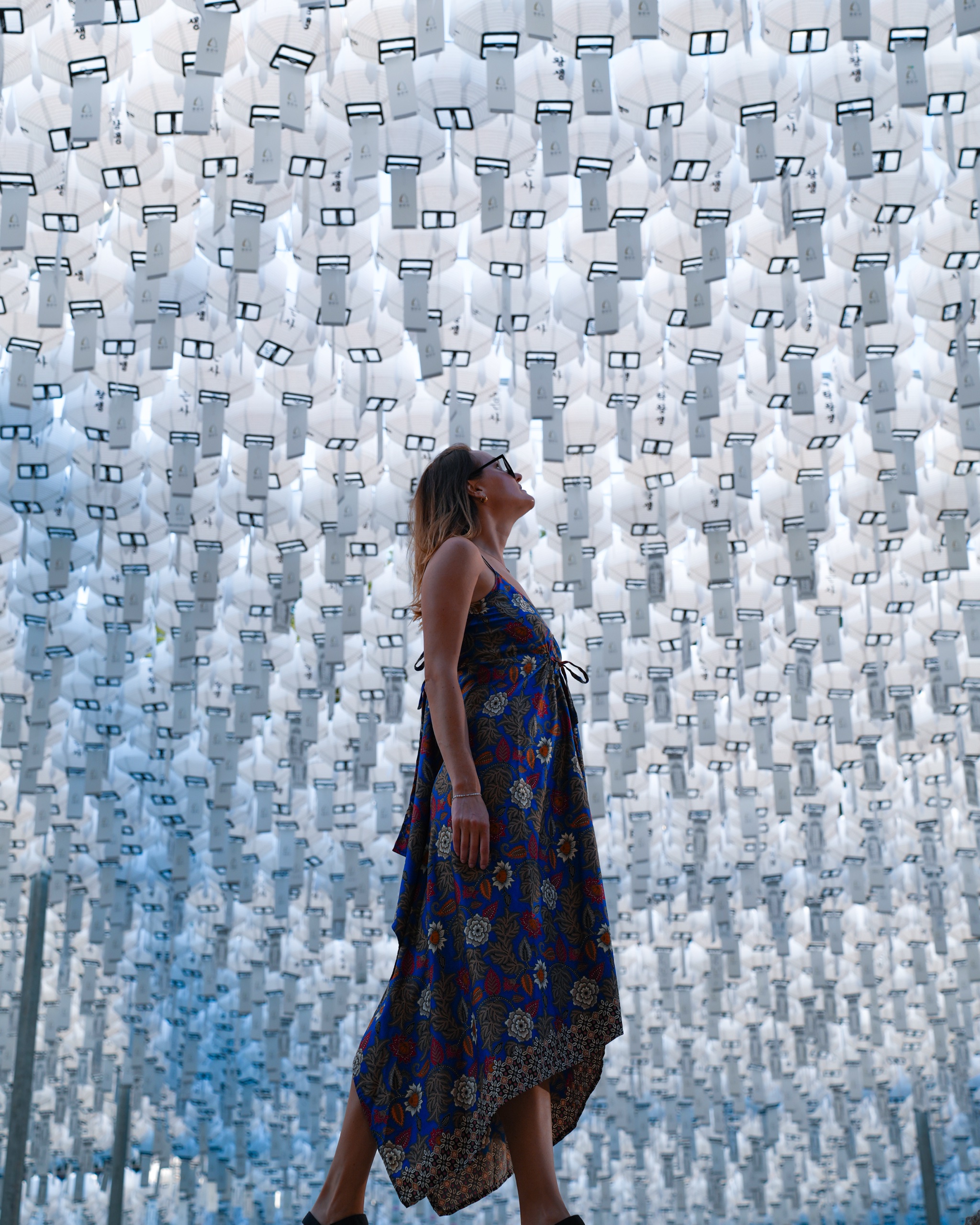Polina standing beneath rows of white lanterns at Bongeunsa Temple