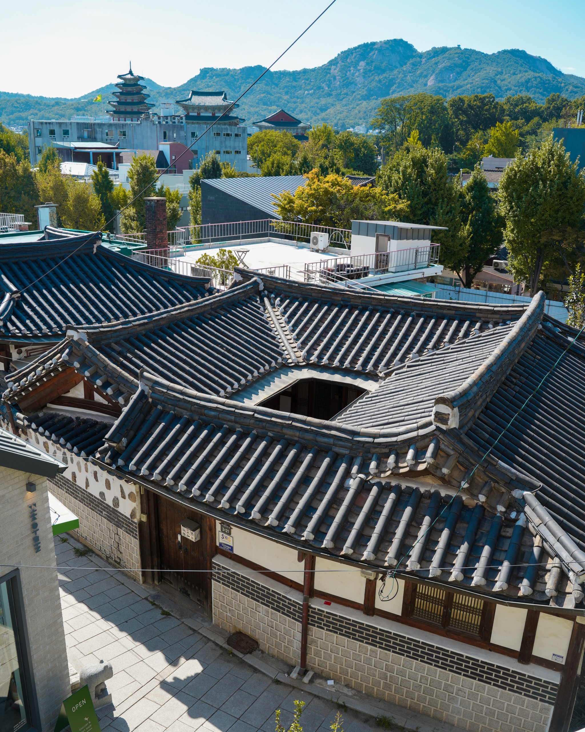 View over hanok rooftops in Bukchon toward a five-story pagoda and mountains