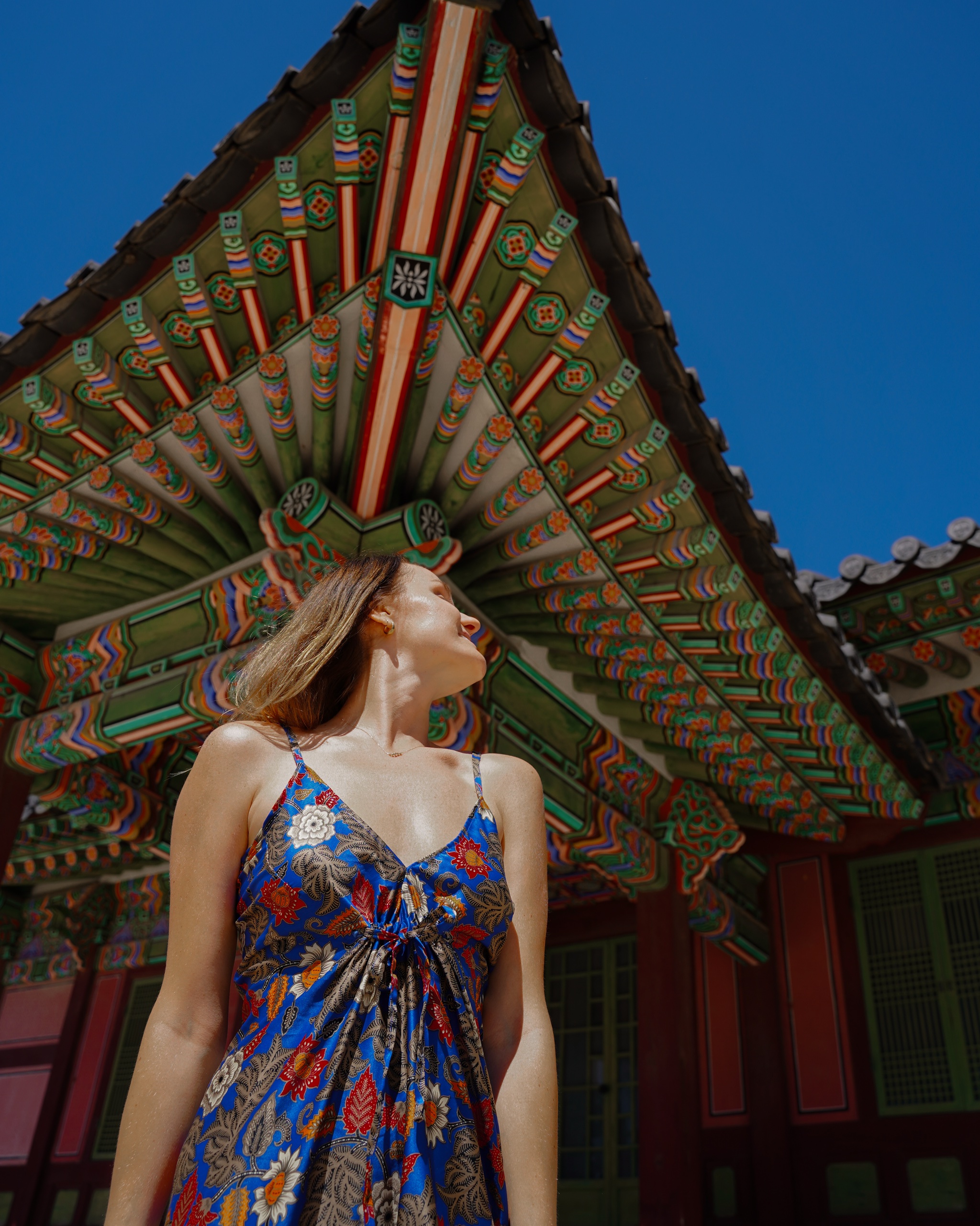 Polina looking up at the dancheong-painted eaves of a Changdeokgung pavilion