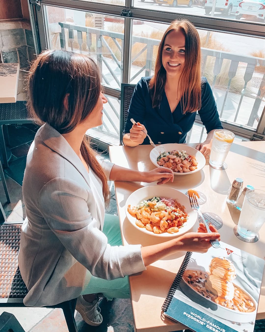 Polina and a friend eating bowls at a table at BJ's Restaurant